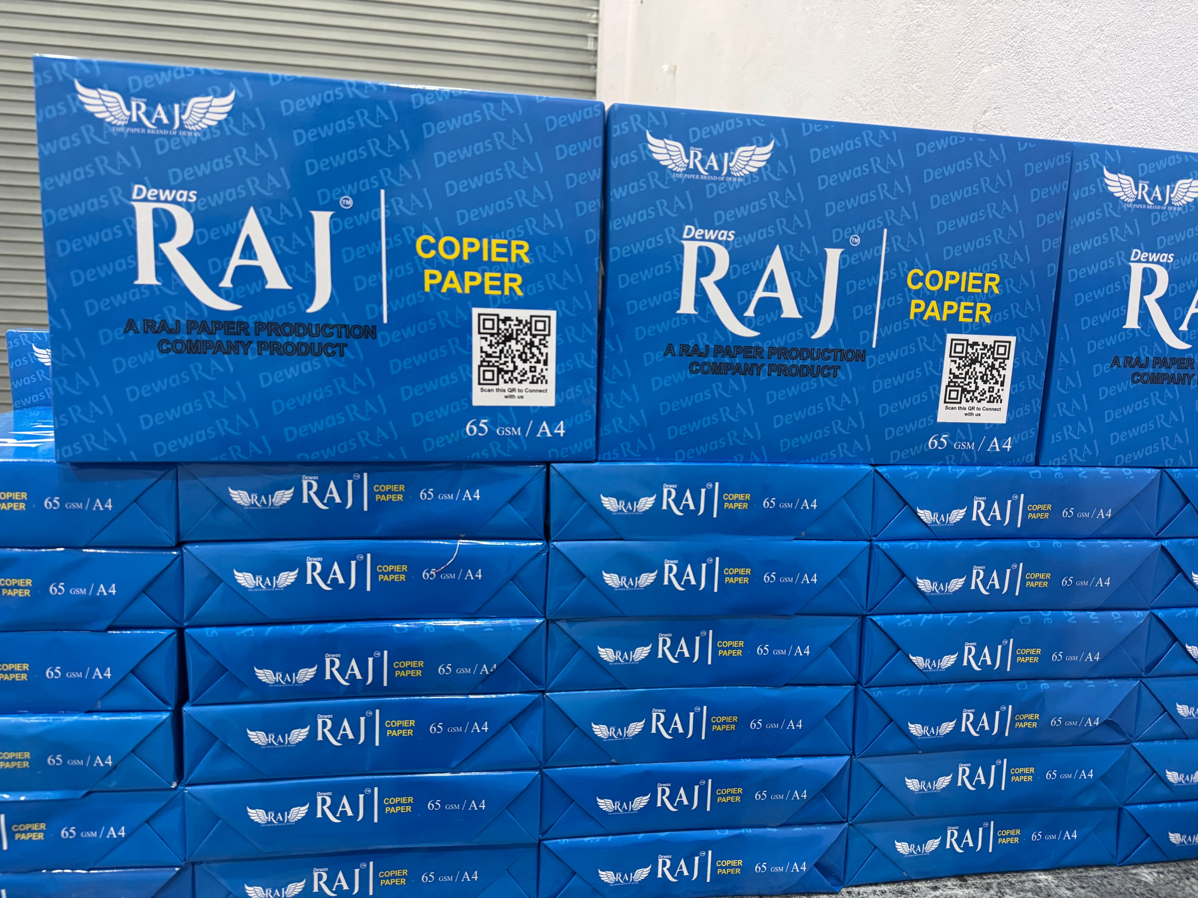 Stacks of Dewas Raj 65 GSM A4 copier paper cartons ready for dispatch