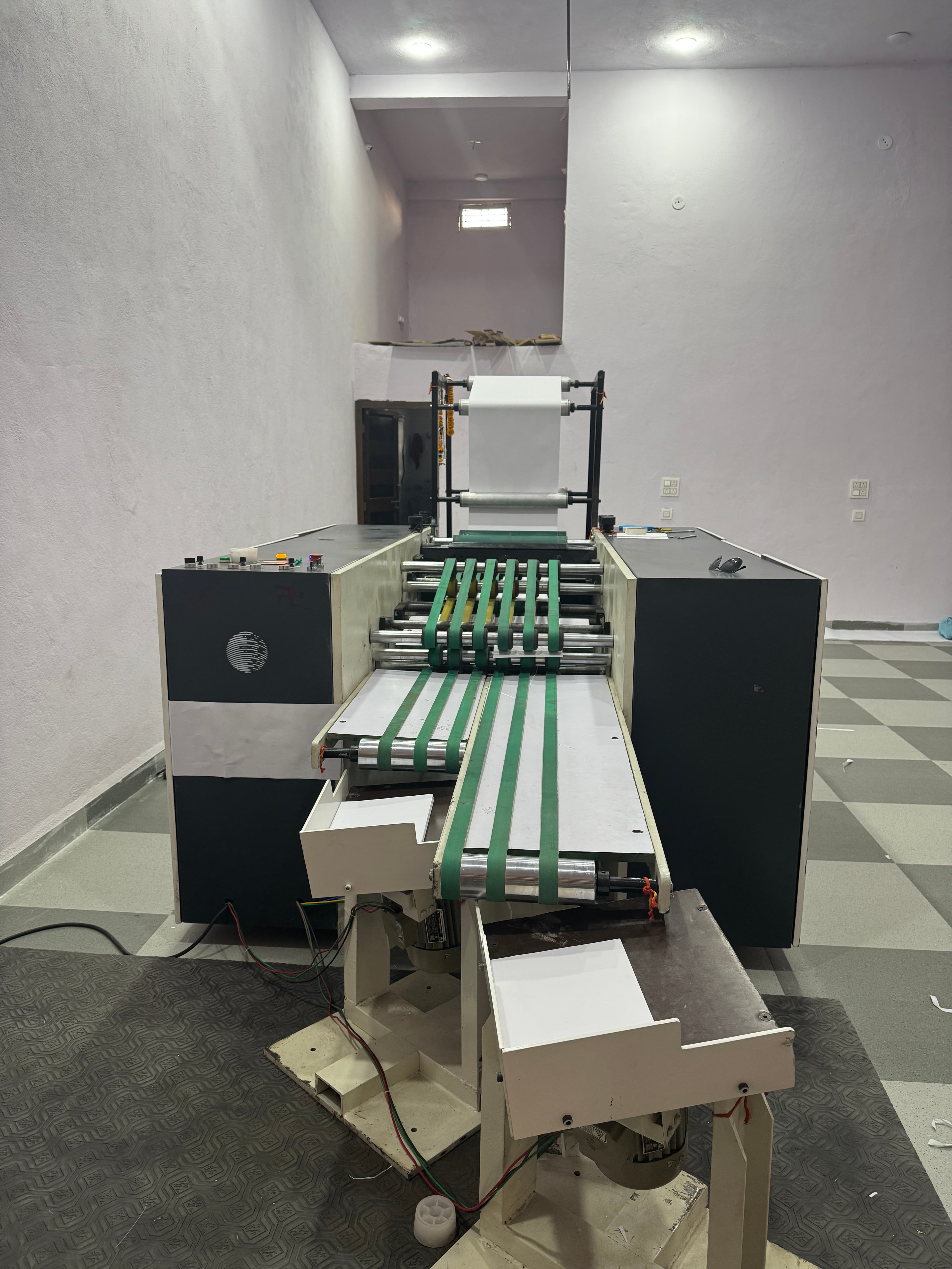 Industrial sheet cutting machine running paper through belted feed rollers